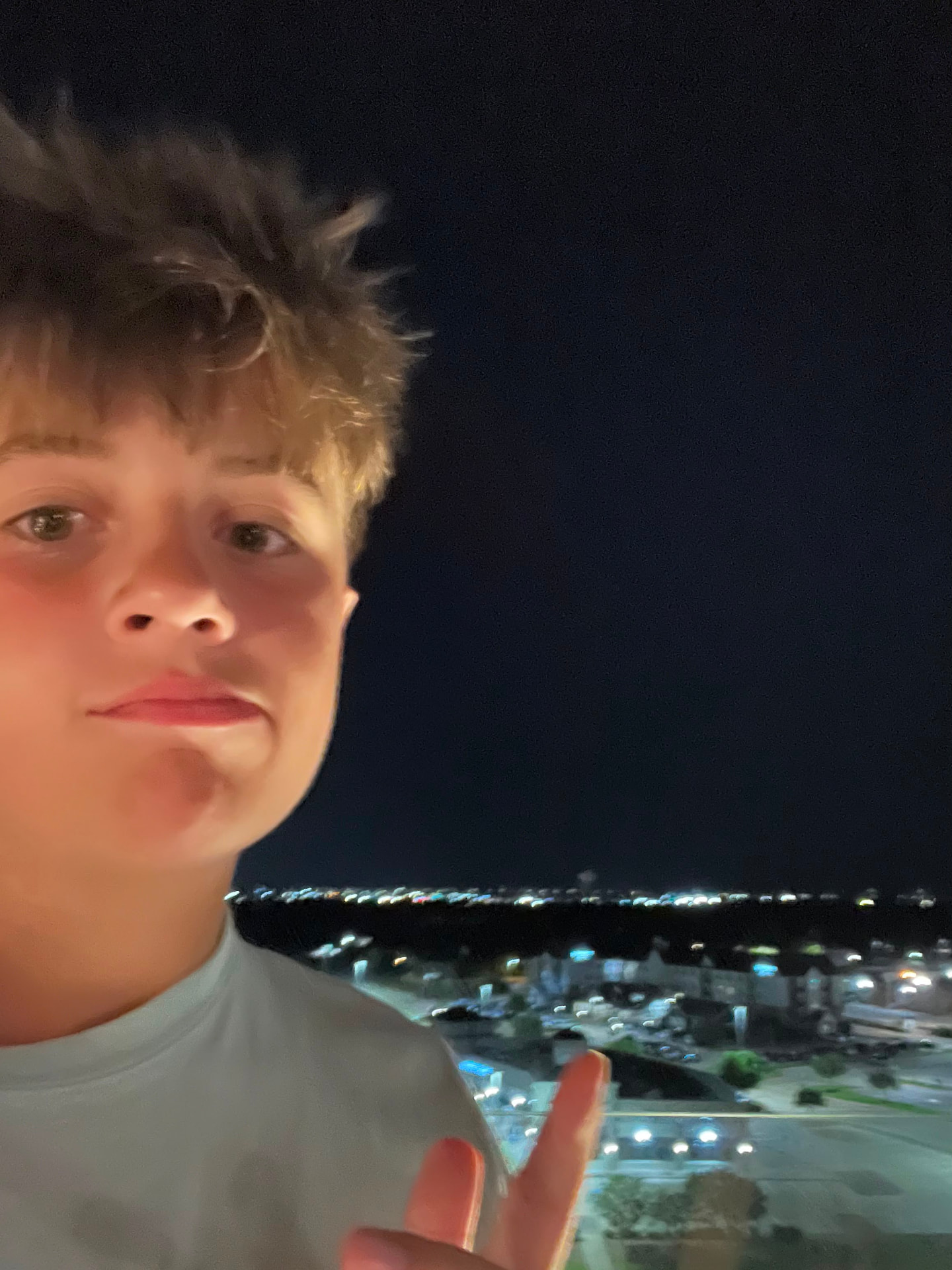 Joe, ASHEZ co-founder from Nebraska, photographed at night with city lights behind him