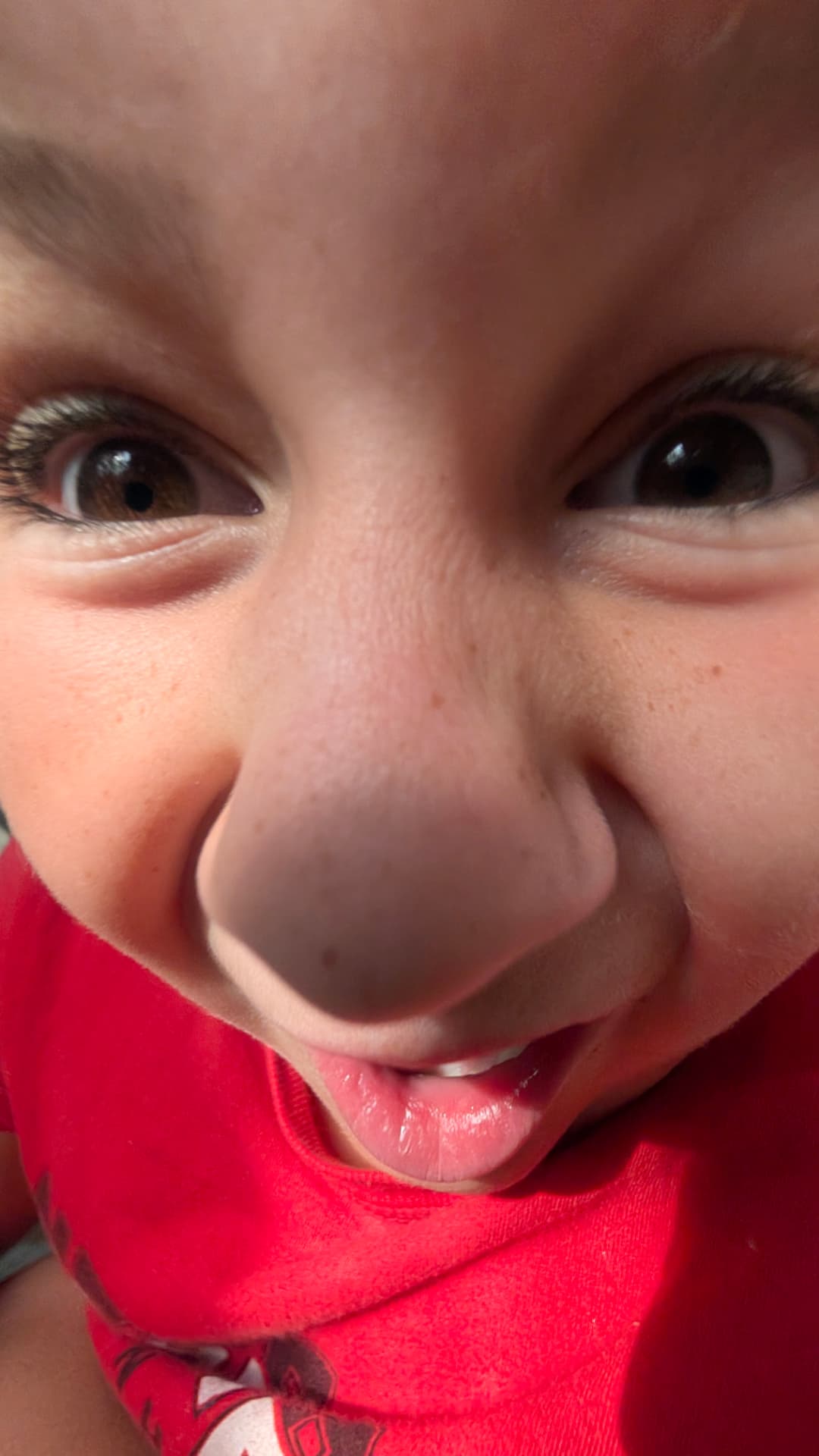 Ollie making a silly face up close in a red shirt